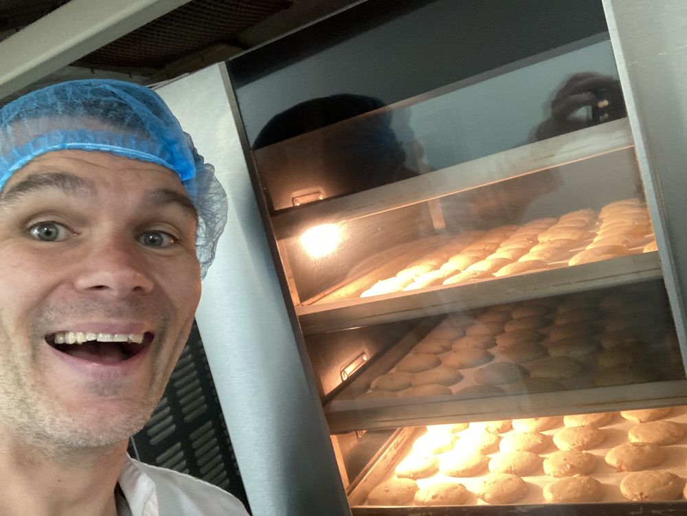 Ro in a hairnet grinning beside a rack of biscuits in the oven